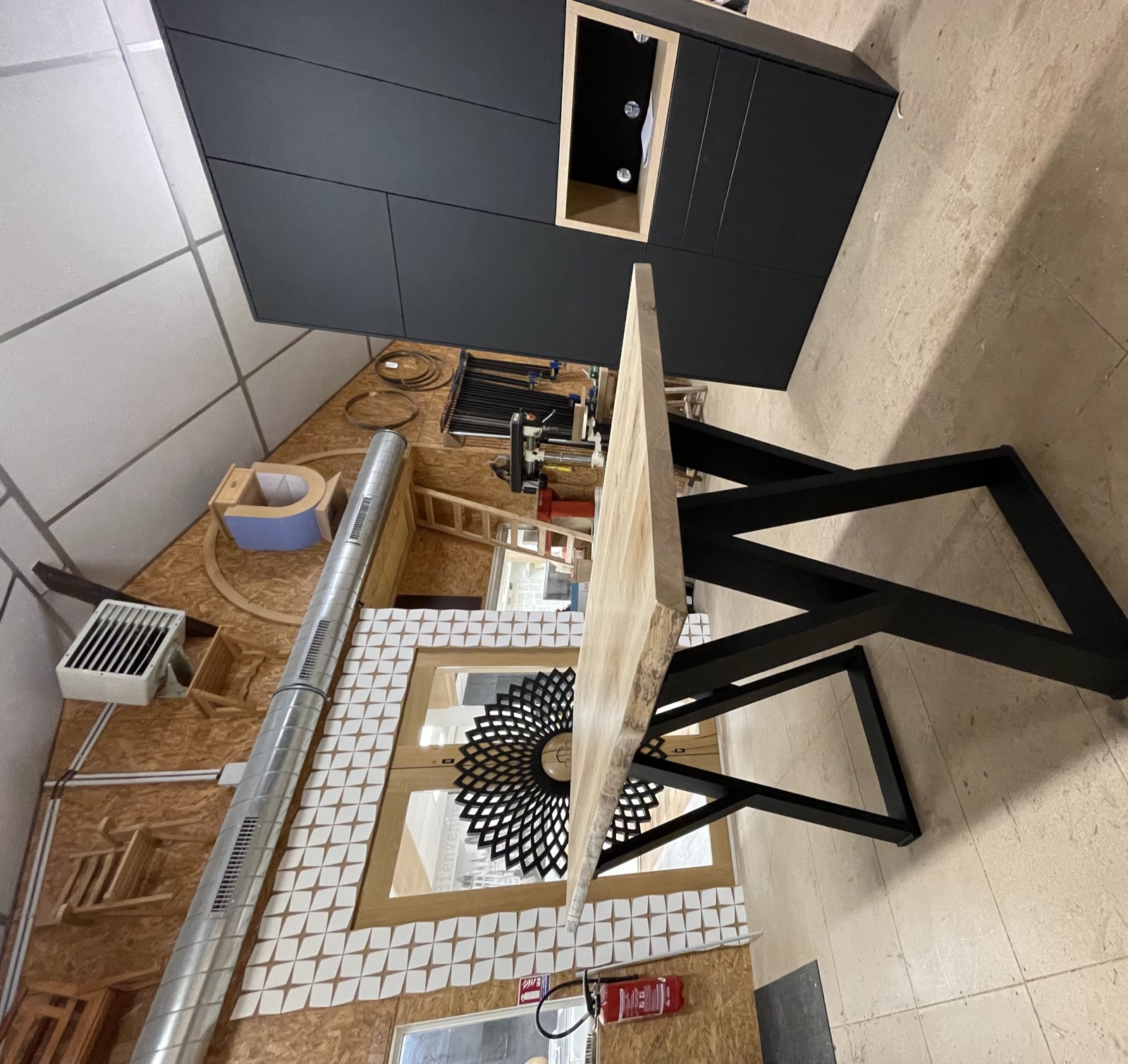 Table à plateau bois et meuble sombre présentés dans l'atelier