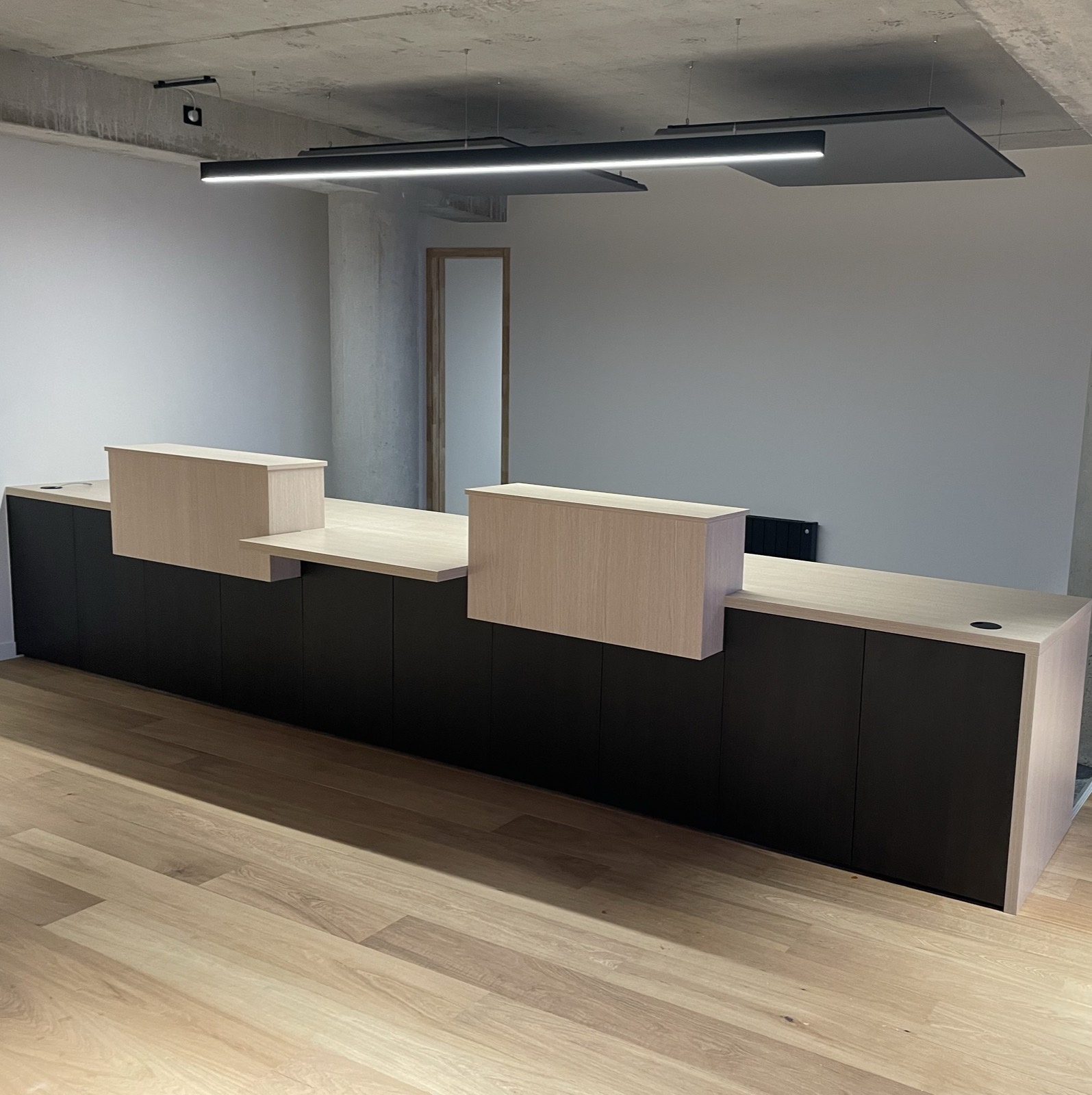 Banque d'accueil sur mesure en bois clair et panneaux sombres